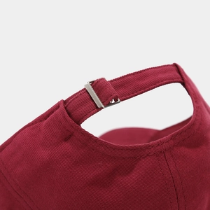 Close-up of adjustable metal buckle and stitching on burgundy cotton baseball cap