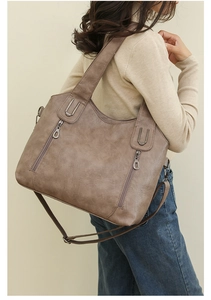 Close-up of tan PU leather shoulder bag featuring dual vertical zippers and metal hardware