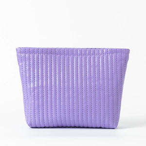 Close-up of purple makeup bag with vertical quilted stitching and trapezoid structure
