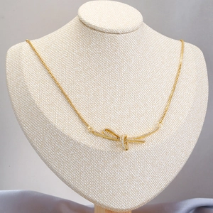 Elegant gold bow necklace with micro-pave cubic zirconia on a luxury jewelry stand