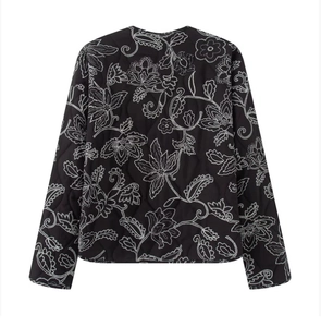 Detail of black quilted jacket with white floral embroidery and high-quality textured finish
