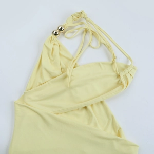 Détail de la robe licou jaune avec des perles dorées décoratives sur l'encolure
