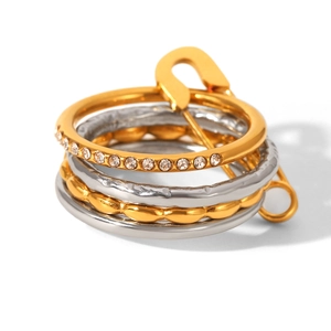 Detailed macro view of multi-layered stainless steel ring set with crystals and safety pin charm