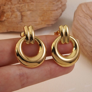 Polished gold circular hoop earrings with striped buckle detail worn on a model