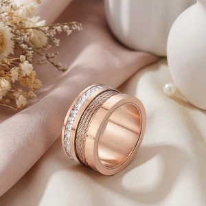 Detailed view of rose gold roman numeral ring with steel cable texture and zircons