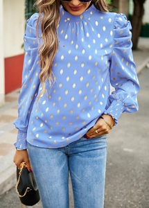 Detail of blue long-sleeve blouse with gold foil patterns and elastic smocked cuffs