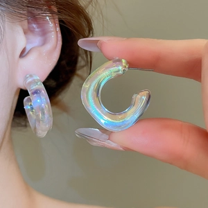 Macro shot of iridescent acrylic C-shape hoop earrings with colorful rainbow finish