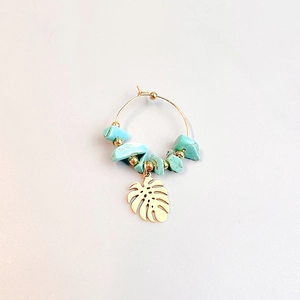 Detail of bohemian gold hoop earrings featuring turquoise stones and monstera leaf charm