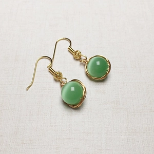 Détail de boucles d'oreilles oeil-de-chat vert avec fil doré de haute qualité