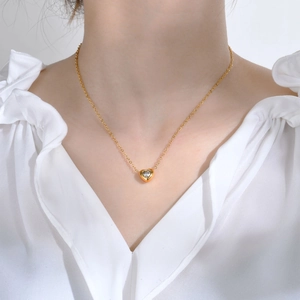 Close-up of heart-shaped gold pendant with white zircon on a fine link chain on model