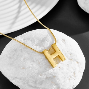 Close-up of golden stainless steel H-letter pendant with fashion engraving detail