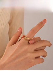 Dettaglio di un anello a V dorato a strati con finitura intrecciata sulla mano