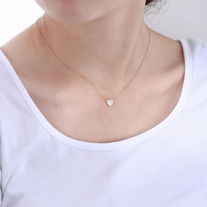 Close-up of a s925 gold heart necklace with zircon pave on the neck of a model