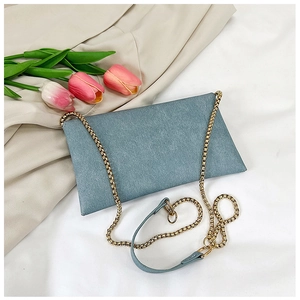 Detail of light blue denim envelope bag with gold chain strap and pink tulips