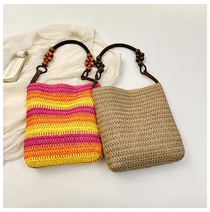 Detail of straw handbags with rainbow stripes and wooden bead handles on white background