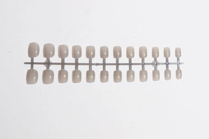 Detailed view of 24 short square nude press-on nails on a plastic runner set