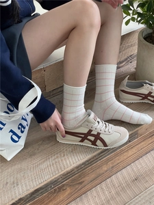 Close-up of white middle tube socks with pink plaid pattern paired with casual sneakers