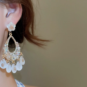Close-up of pearl flower drop earrings with crystal tassels on a female model