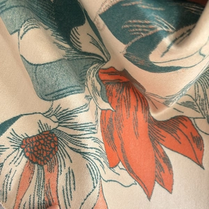 Close-up of beige cashmere-like scarf fabric with elegant blue and orange floral pattern