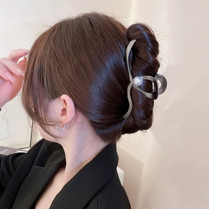 Detail of grey metal hair claw clip with white pearl on French twist hairstyle