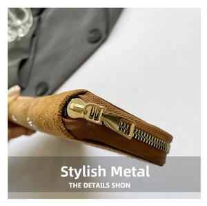 Detailed macro view of the golden metal zipper and stitching on the brown suede handbag