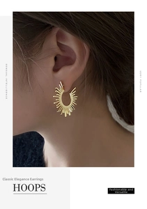 Detail of golden fan-shaped sunburst hoop earrings worn on a model for modern style
