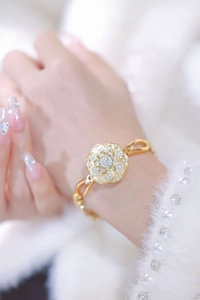 Close-up of golden camellia flower bracelet watch featuring sparkling crystal pavé