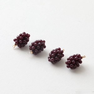 Macro shot of four dark red grape resin charms with gold rings for DIY jewelry