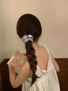 Close-up of silver metallic scrunchie texture with reflective surface on a ponytail