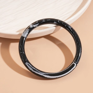 Détails du bracelet en acrylique marbré noir et blanc sur une assiette en céramique