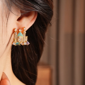 Close-up of gold-plated castle earring with multicolor zircon stones on a model's ear