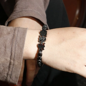 Close-up of a black stainless steel skull link bracelet worn on a male wrist in punk style
