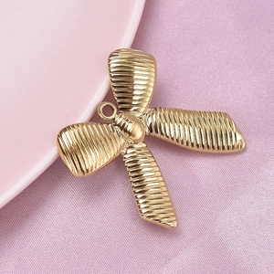 Detailed macro shot of a gold bow-shaped pendant in 304 stainless steel with striped texture