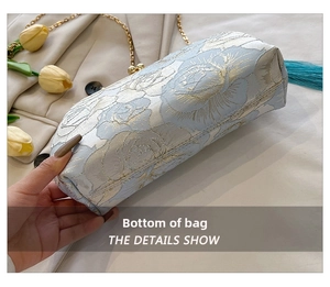 Detailed bottom view of an embroidered shell bag with floral jacquard and blue tassel