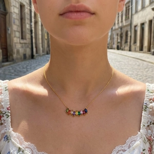 Close-up of a gold necklace with nine colorful marquise-cut gems worn by a model