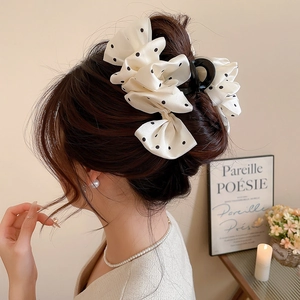 Detail of cream fabric hair claw with black polka dots and French bow for high ponytail