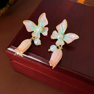 Vintage butterfly earrings with pink glaze, pearls and flower pendants on a wooden box