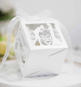 Detailed laser-cut pattern on white wedding favor box with thank you text and silk ribbon