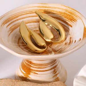 Golden abstract geometric earrings in a ceramic bowl, minimalist stainless steel design