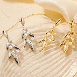Elegant gold and silver leaf earrings with pearls on a textured glass tray background