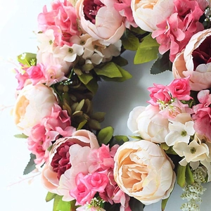 Close-up of pink and cream peony wreath with hydrangea flowers and green foliage