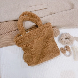 Dettaglio di borsa in peluche marrone caldo con consistenza soffice su sfondo beige
