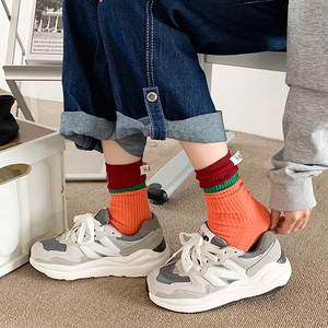 Close-up of color-block striped crew socks in orange and burgundy with SA fabric label