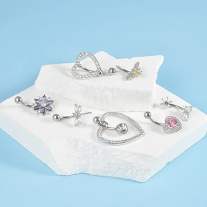 Detail of diverse navel rings with heart and floral designs on a white pedestal