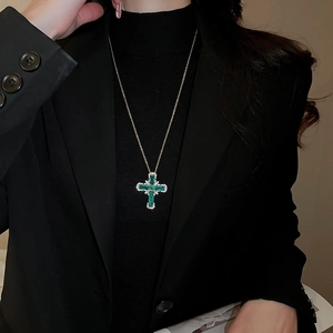 Détail du pendentif croix en résine verte avec zircons sur une chaîne en or fin