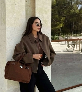 Gros plan sur une veste en laine marron et un sac à main en cuir de luxe en extérieur