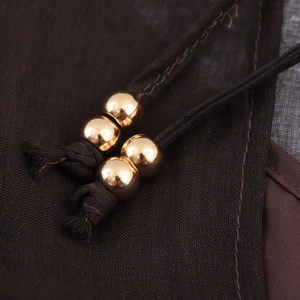Elegant bohemian chiffon dress detail featuring woven drawstrings with polished gold beads