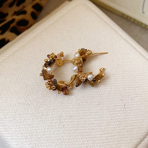 Detailed macro view of vintage gold hoop earrings with tiger eye stones and white pearls