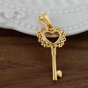 Gros plan d'un pendentif clé en forme de cœur plaqué or 24K sur une surface en bois