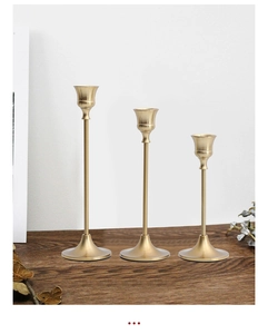 Set van drie luxe mat messing kandelaars in verschillende hoogtes op houten tafel